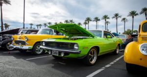 A vibrant collection of vintage cars displayed in an outdoors car show parking lot, showcasing classic automotive design.