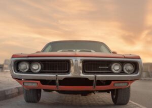 Front view of a classic Dodge muscle car under a vibrant sunset in Sharjah, UAE.